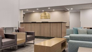 A modern lobby with seating arrangements, a reception desk, and a wooden panel wall. - Wingate by Wyndham Green Bay/Airport (Green Bay)