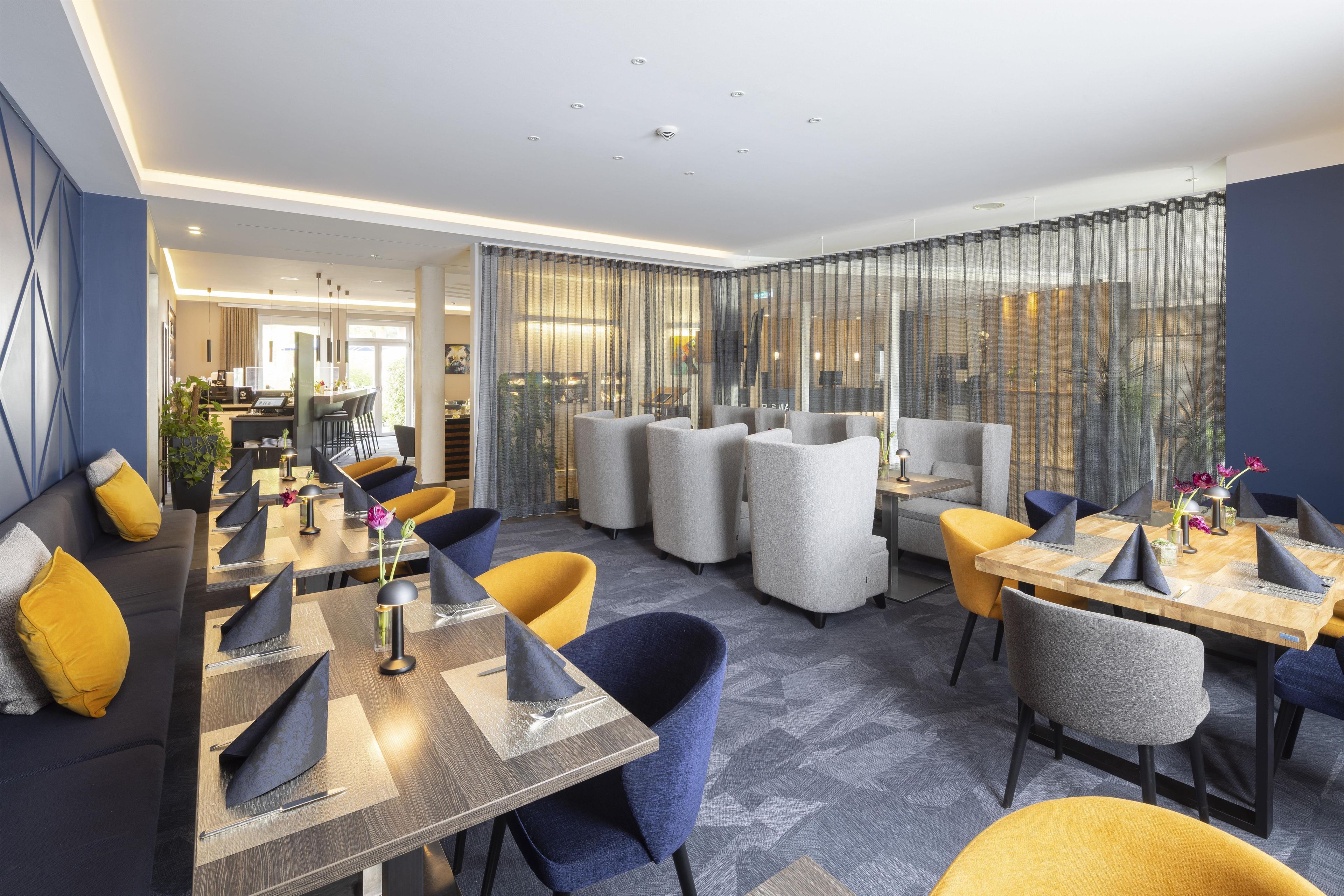 Eine moderne Hotelhalle mit Barbereich, Sitzgelegenheiten und Blick durch eine Glaswand.