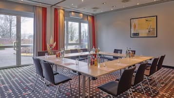 Ein Konferenzraum mit einem langen Tisch, Stühlen und einem großen Fenster mit Vorhängen.
