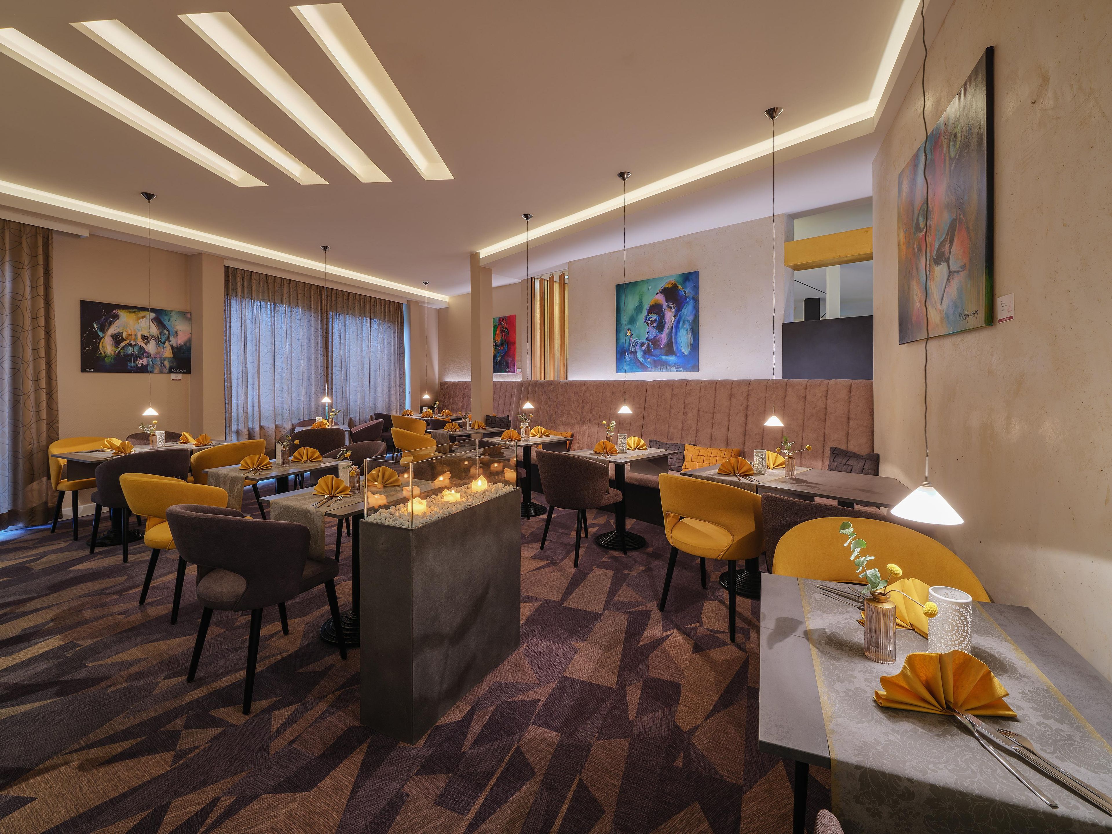 Un espace de restauration moderne, doté de plusieurs tables, de chaises et d’un éclairage d’ambiance.