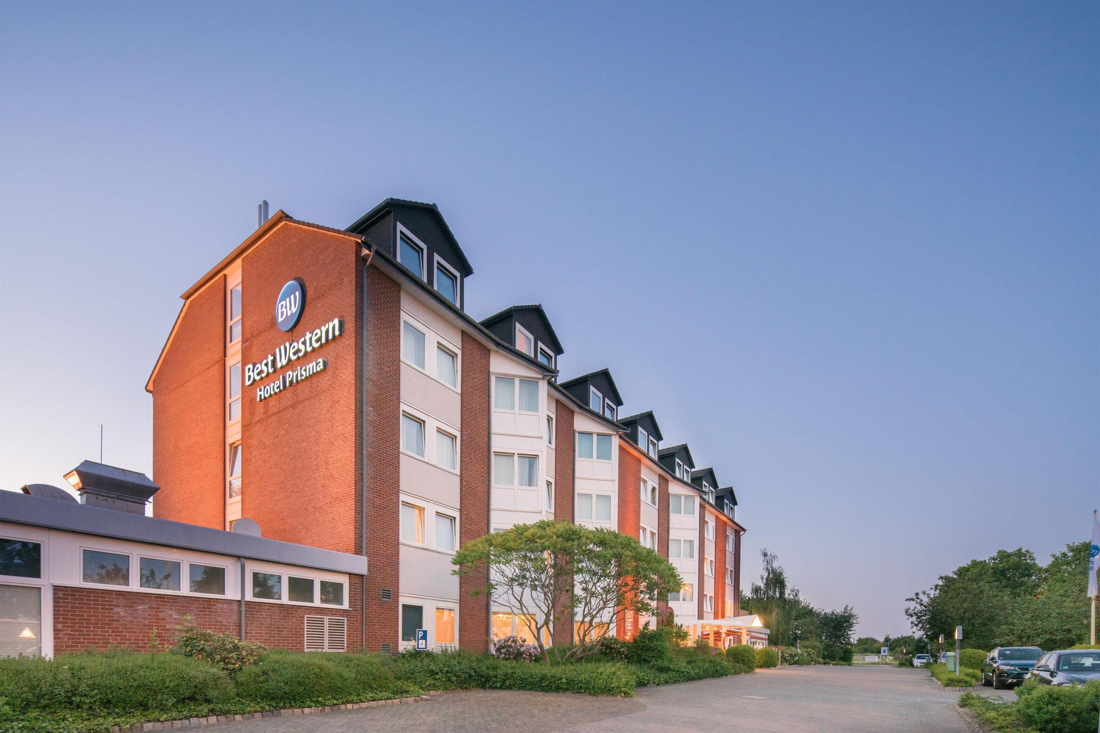 Ein mehrstöckiges Hotelgebäude mit einem auffälligen 'BW'-Logo und der Aufschrift 'Best Western Hotel Prisma' an der Fassade.