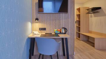 A modern room with a desk, chair, TV, and a shelf with a kettle.