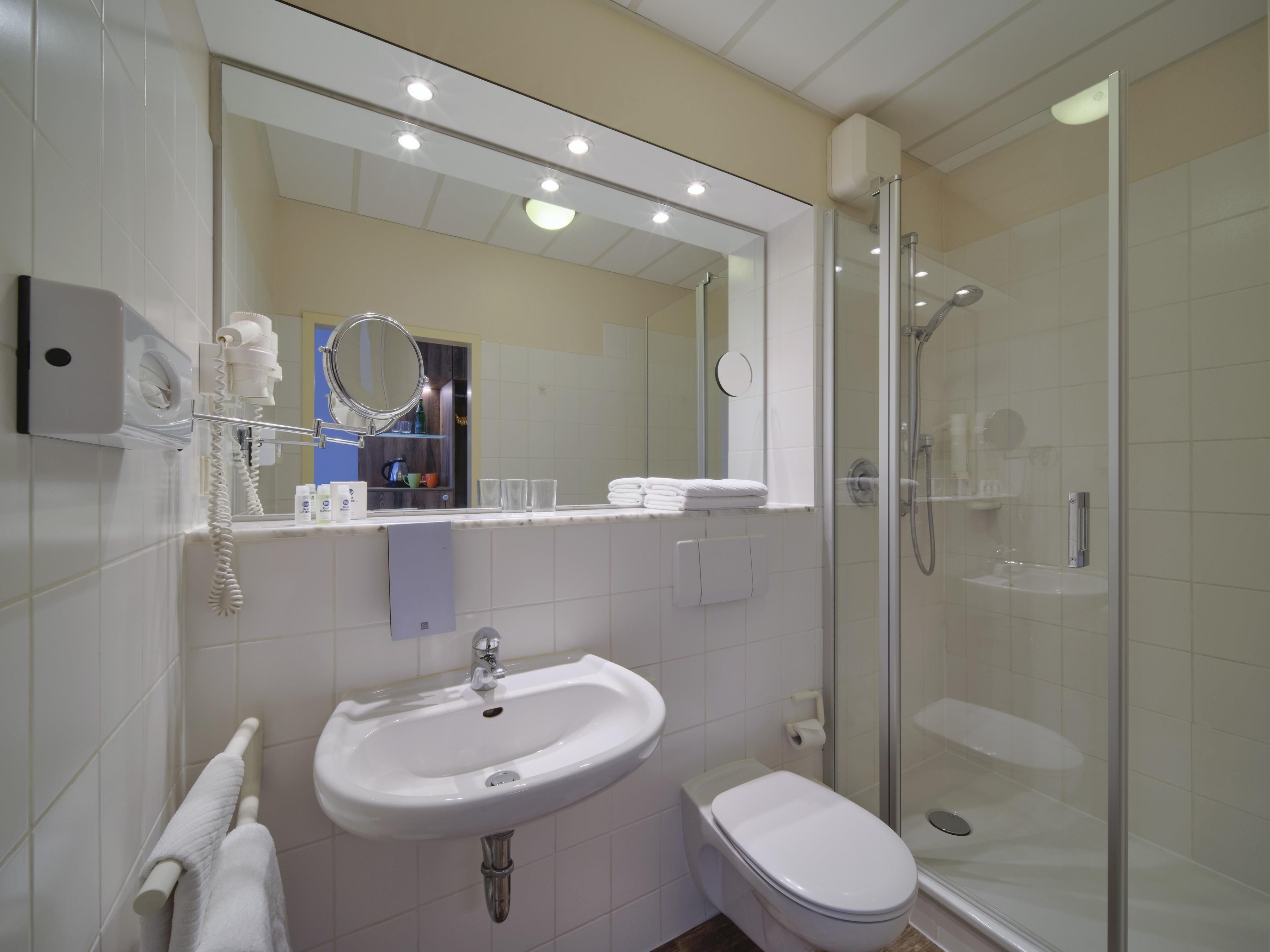 A modern bathroom with a sink, toilet, and glass-enclosed shower.