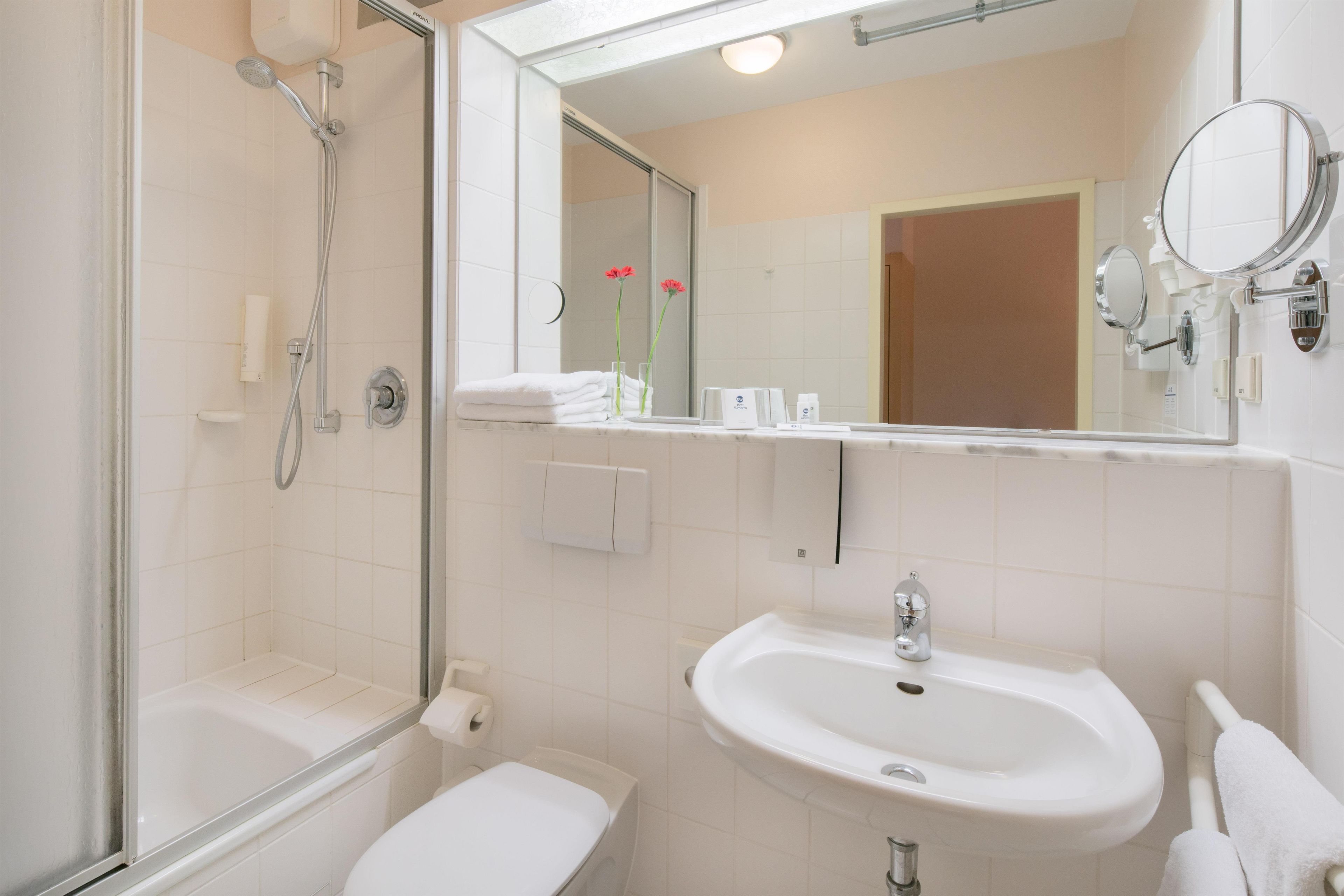 Ein Badezimmer mit Dusche, Toilette, Waschbecken und Spiegel.