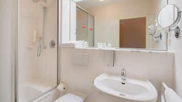 A bathroom with a shower, toilet, sink, and a mirror.