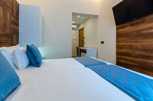 Ένα υπνοδωμάτιο με ένα κρεβάτι, μαξιλάρια, ένα γραφείο και μια τηλεόραση.