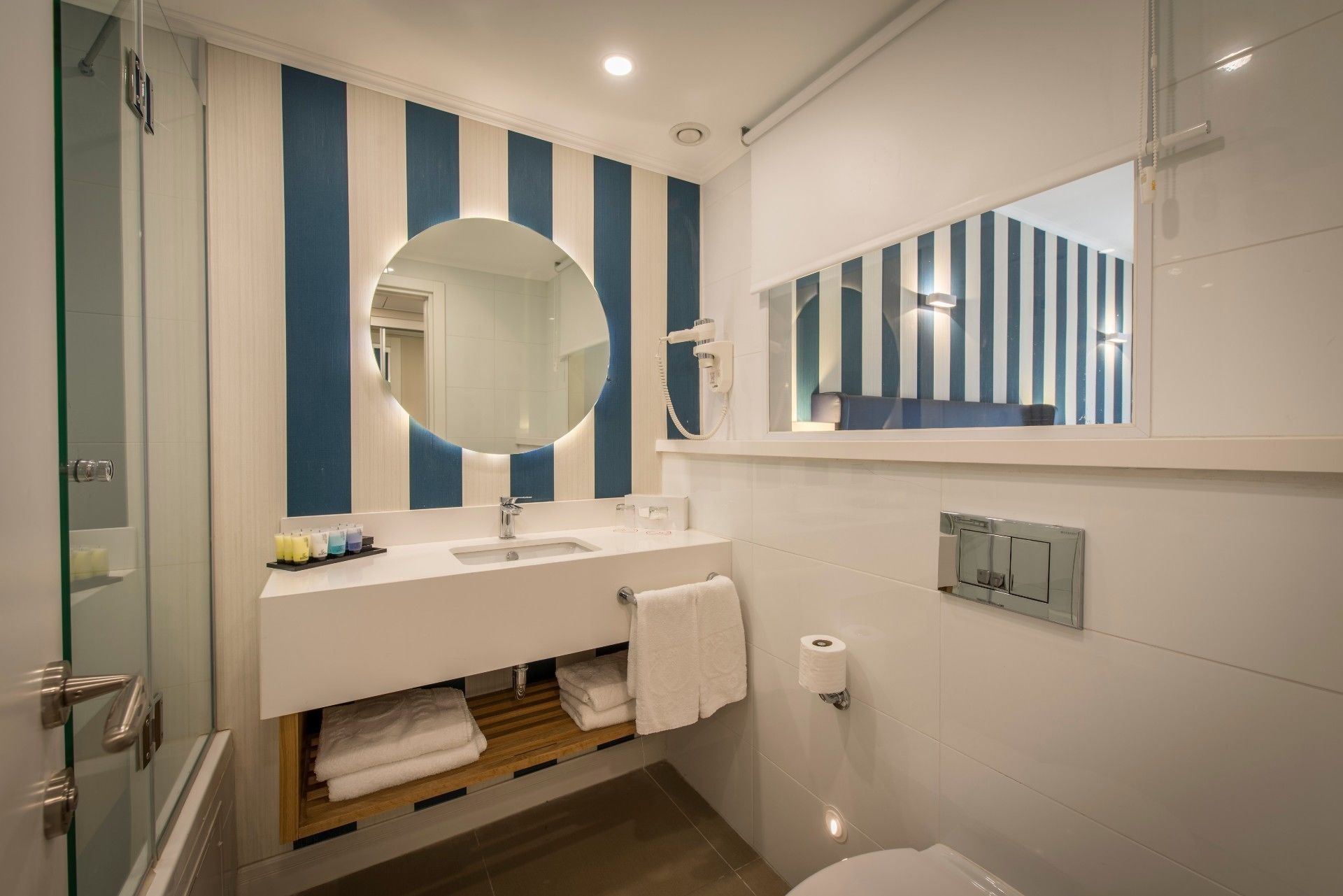 A modern bathroom with a white sink, a large mirror, and a shower enclosure.