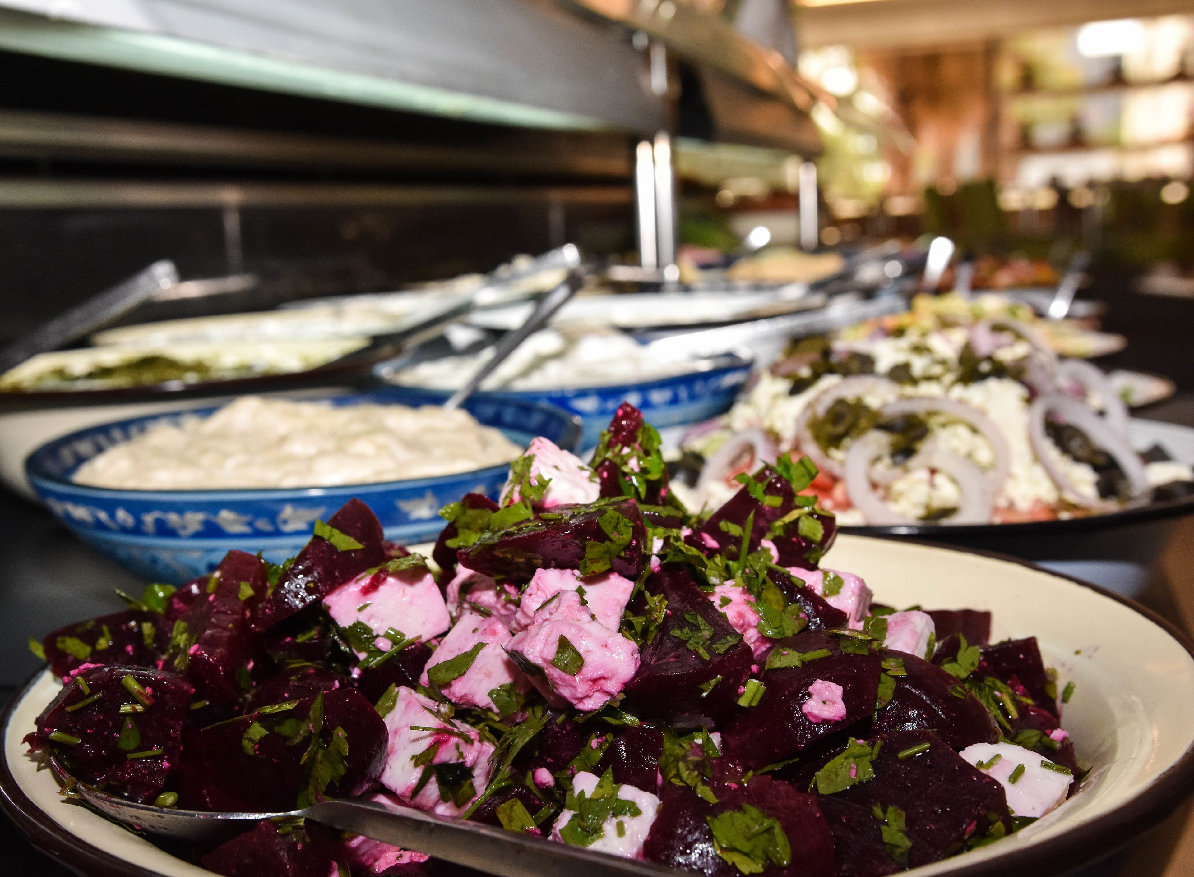A buffet with various dishes including a beet salad, a bowl of dip, and a plate with a different salad.