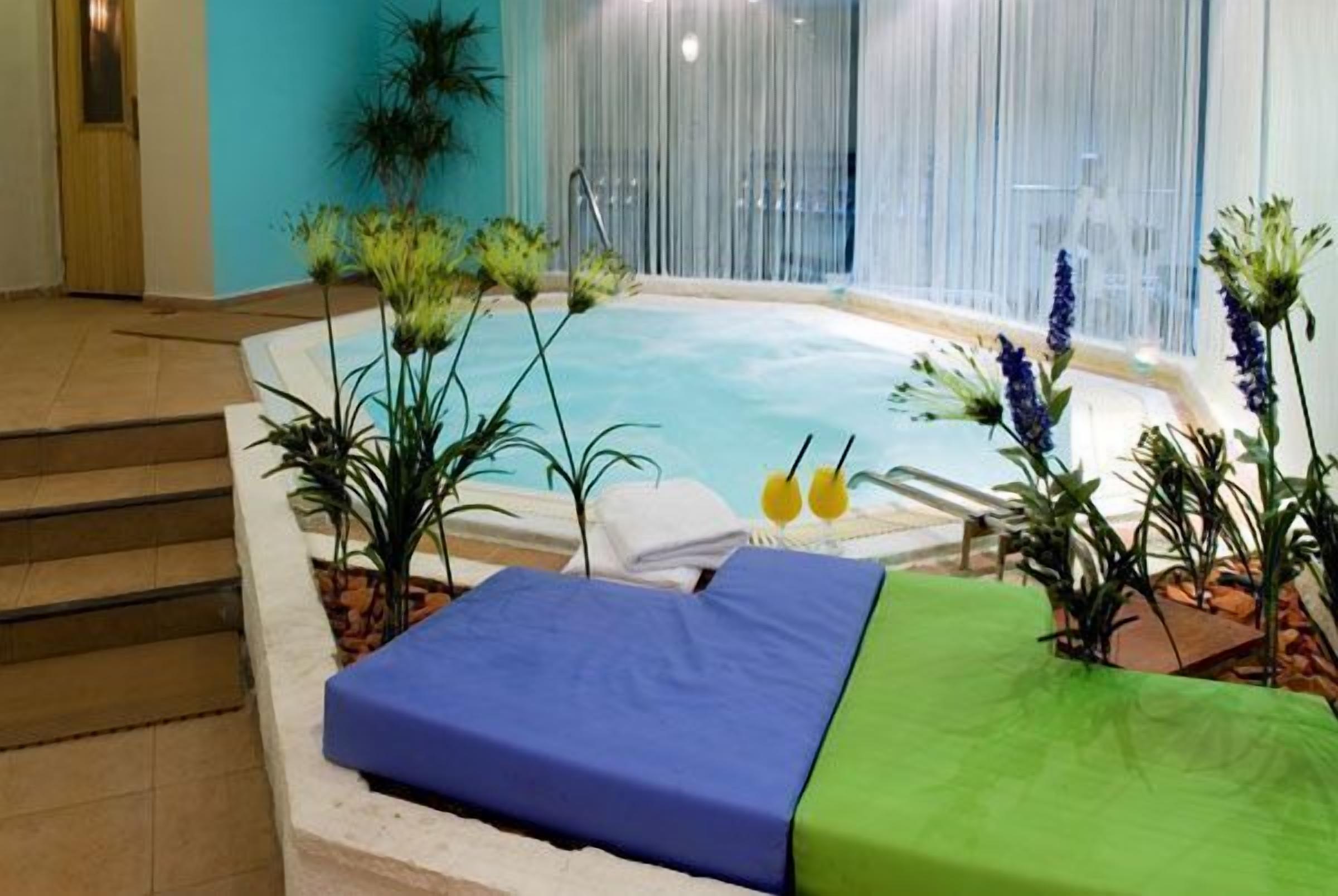 A spa area with a hot tub, two lounge chairs, and various plants.