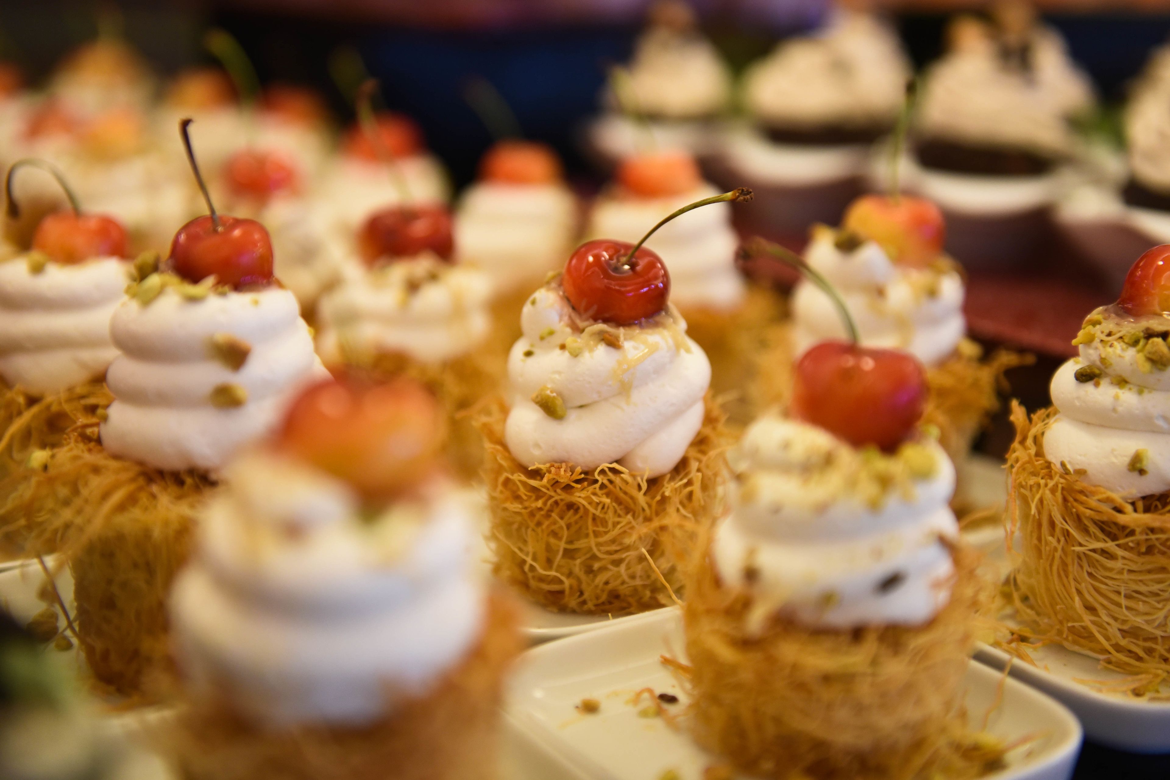 Une présentation de desserts avec de la crème fouettée et des cerises, le tout disposé sur un lit de paille.
