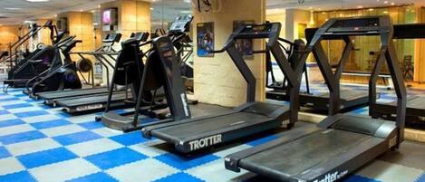 A gym with multiple treadmills and elliptical machines on a blue and white checkered floor.
