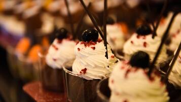 A dessert display with various sweets topped with whipped cream and cherries.