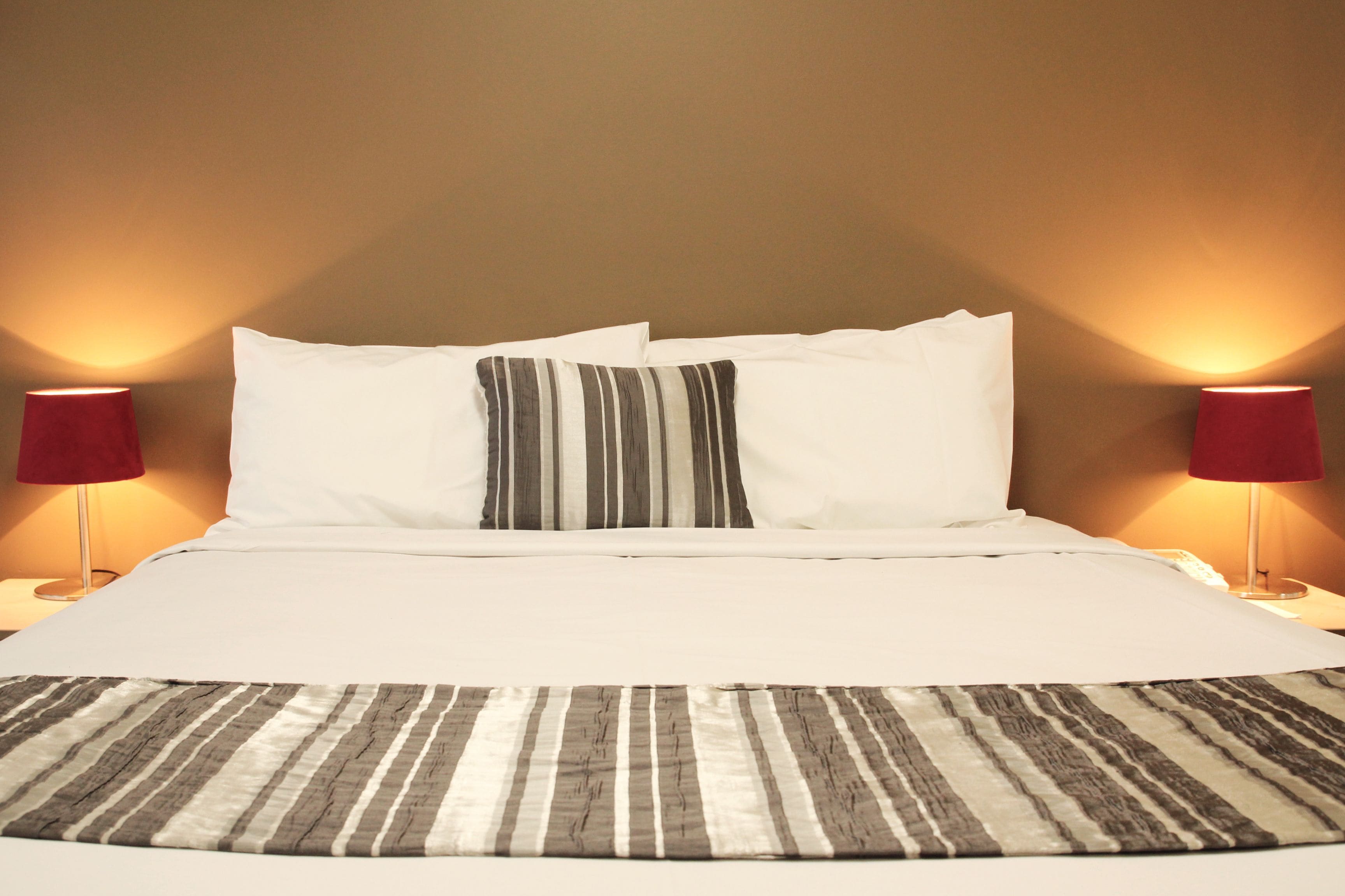 A neatly made bed with white linens, striped pillows, and a striped bedspread.