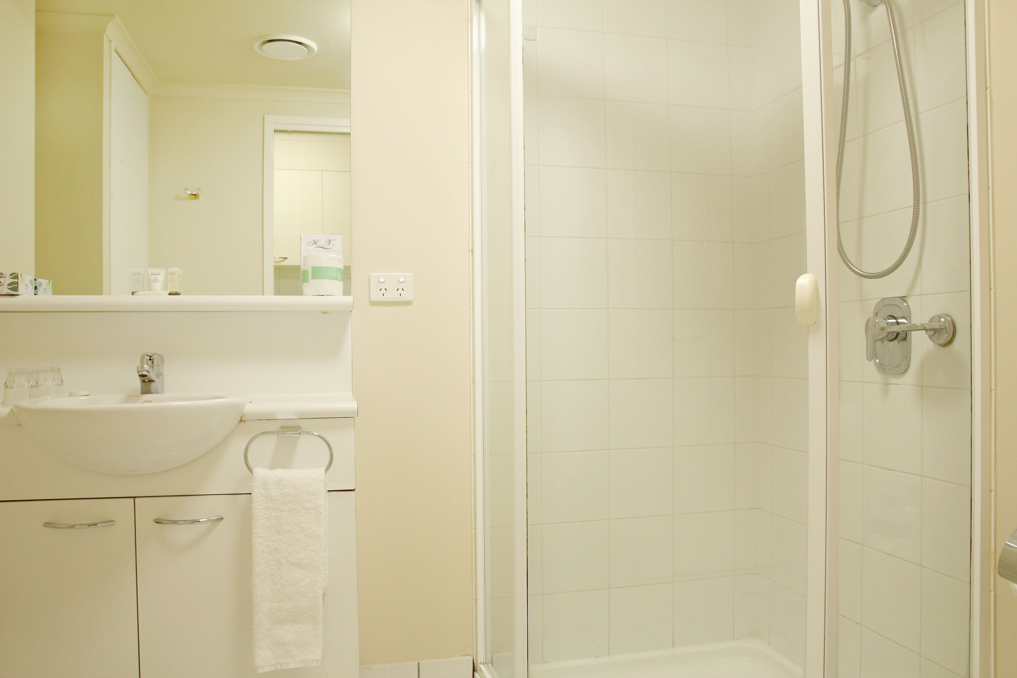 A bathroom with a sink, mirror, and shower.