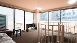 A hotel room with a large window, a desk, a chair, a bed, and a baby gate. - Arrow on Spencer (Melbourne)