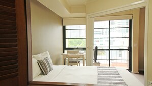 A hotel room with a bed, a desk, and a window with a city view. - Arrow on Spencer (Melbourne)