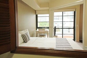 Una habitación de hotel con cama, escritorio y ventana con vista a la ciudad.