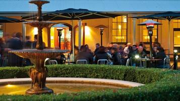 An outdoor dining area with a fountain, tables, and umbrellas.
