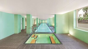 A swimming pool with a tiled floor, surrounded by walls with a green tile pattern.