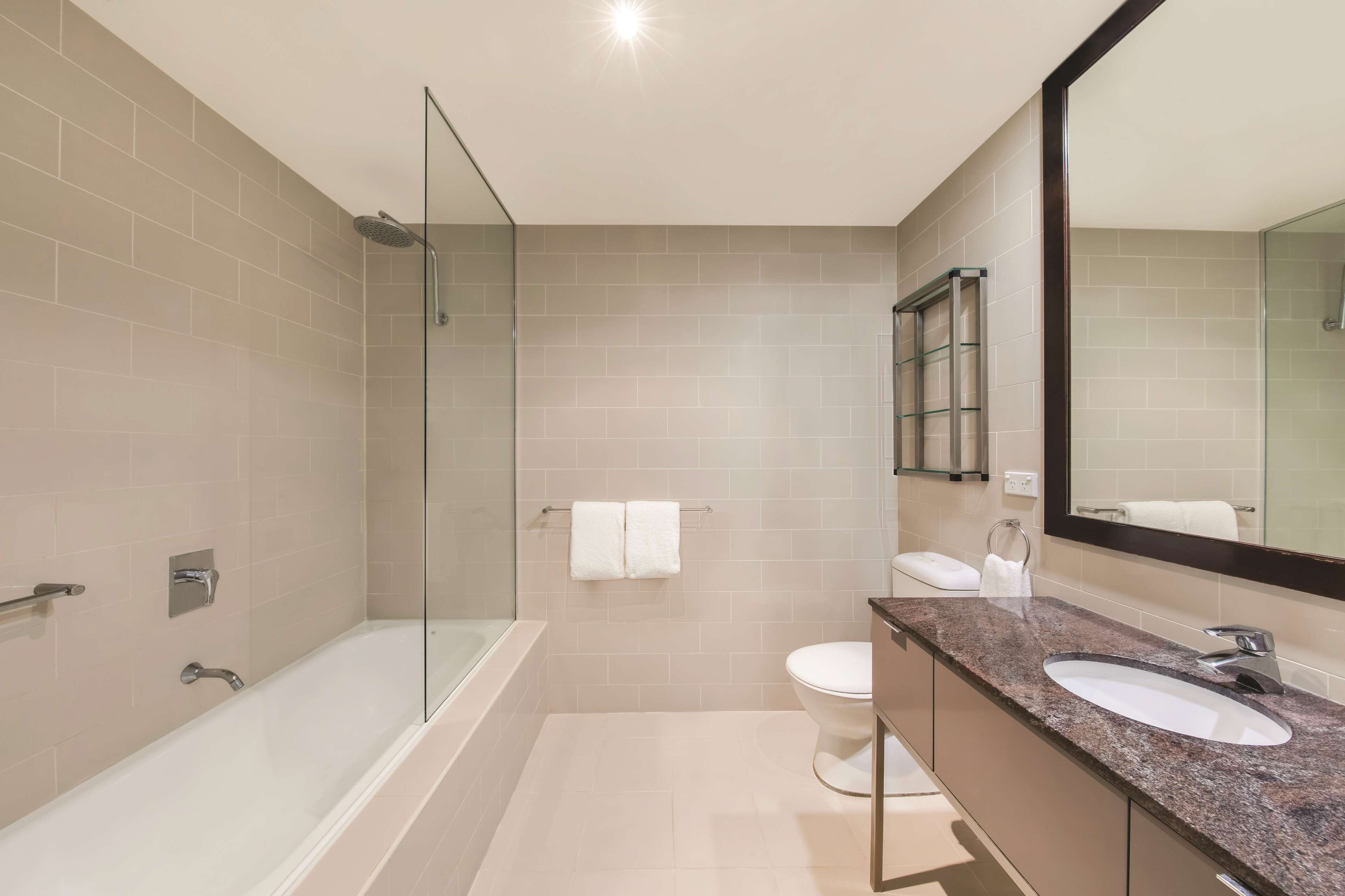 A modern bathroom with a glass shower enclosure, a bathtub, a toilet, and a vanity with a sink.