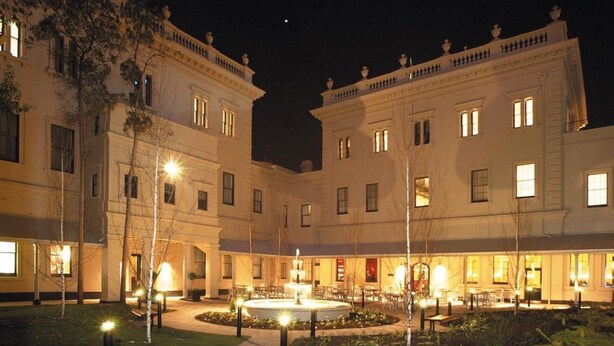 A large, well-lit building with a central courtyard featuring a fountain, surrounded by trees and outdoor seating areas.