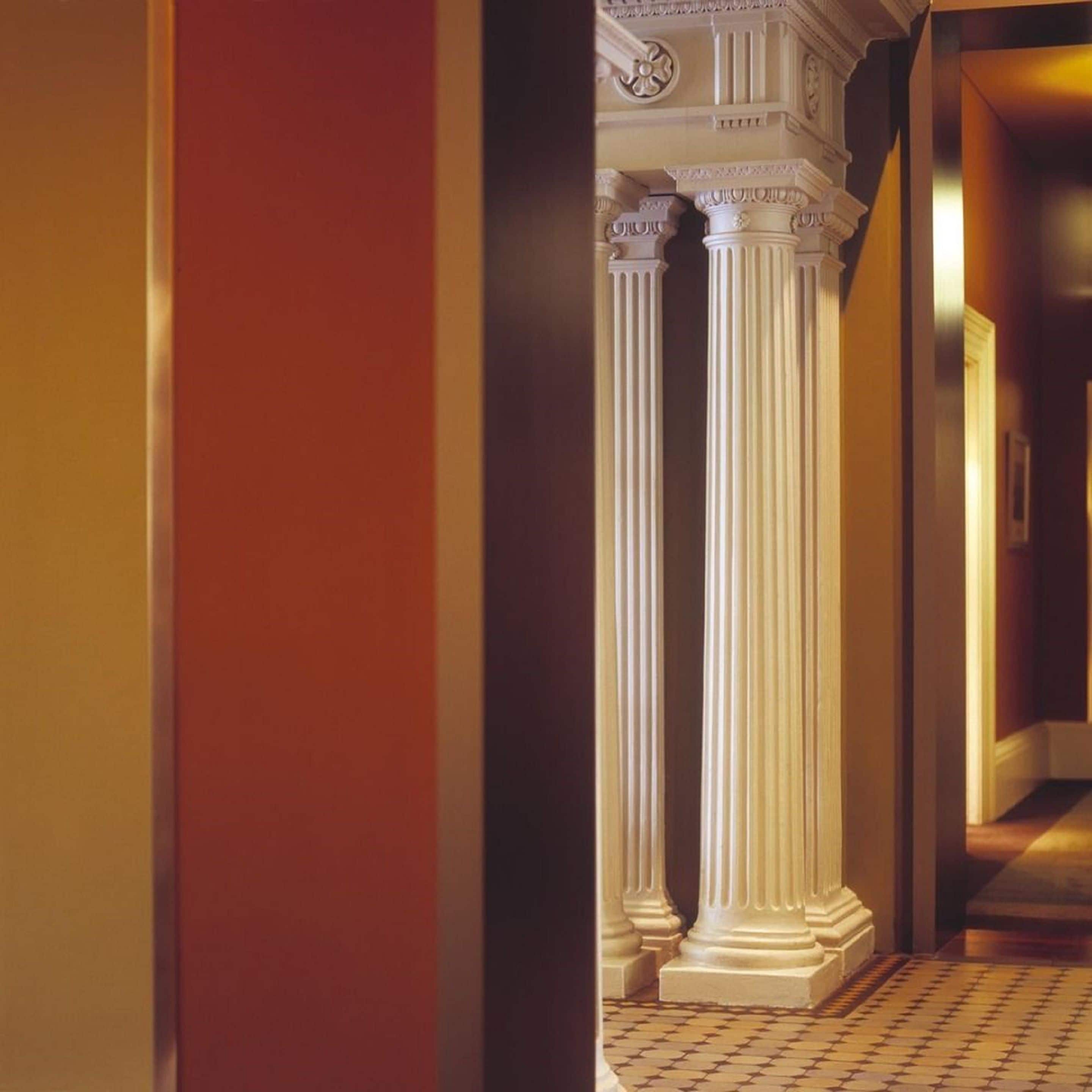 A hallway with white columns and a checkered floor.