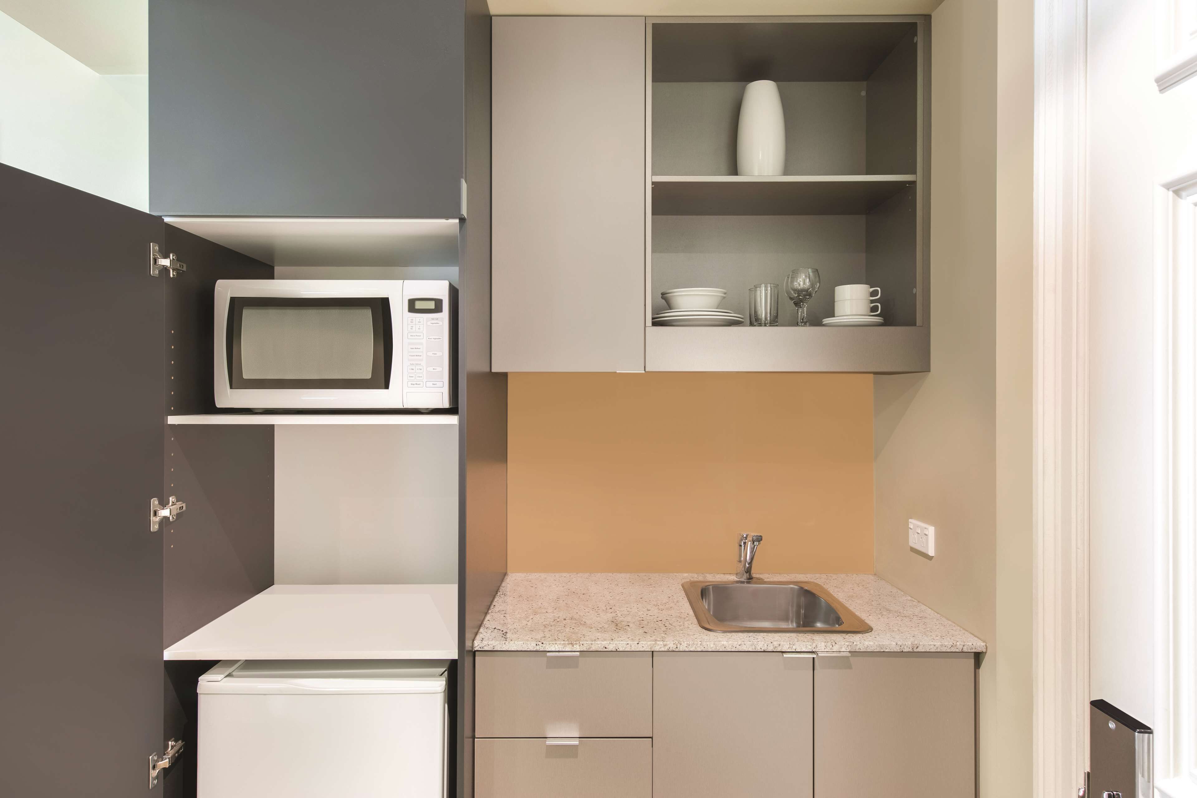 A compact kitchen with a microwave, a sink, and cabinets.