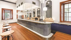 A bar area with a counter, seating, and a large chandelier.