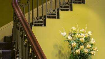 A staircase with a metal railing and a potted plant with white flowers.