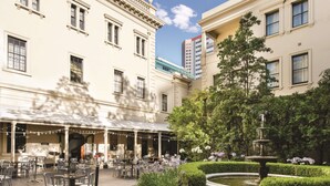 A courtyard with outdoor seating, a fountain, and well-maintained hedges.