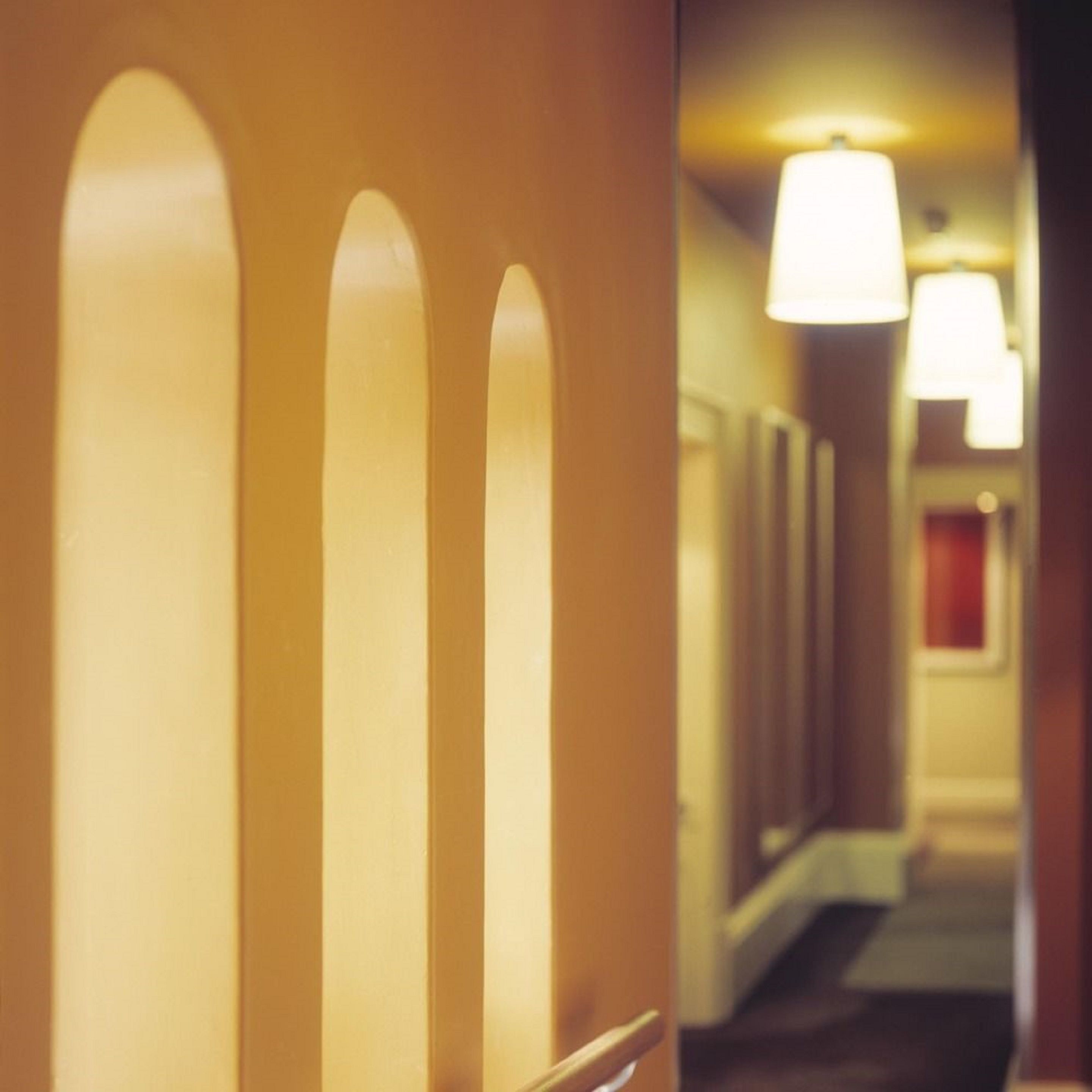 Un couloir d’hôtel avec des portes en arc et un éclairage suspendu au plafond.