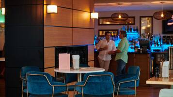 Een bar met blauwe stoelen, een witte tafel en een open haard.