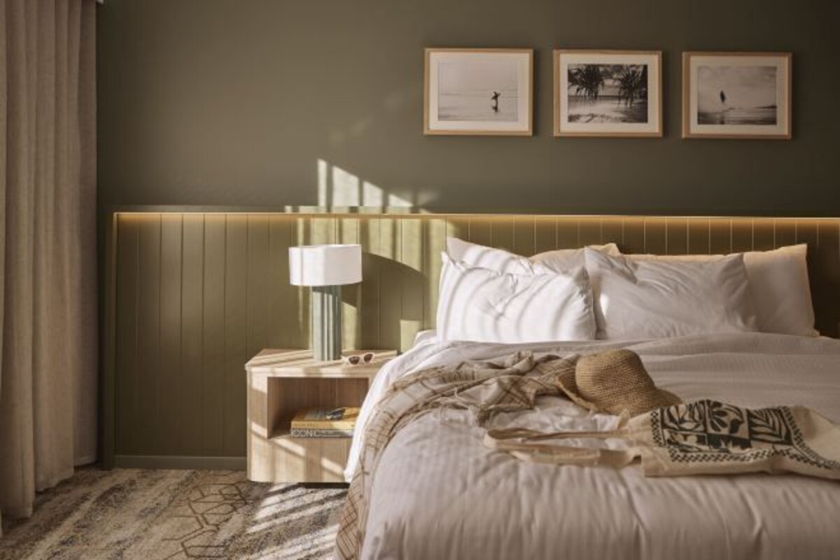 A hotel room with a bed, bedside table, lamp, and wall art.