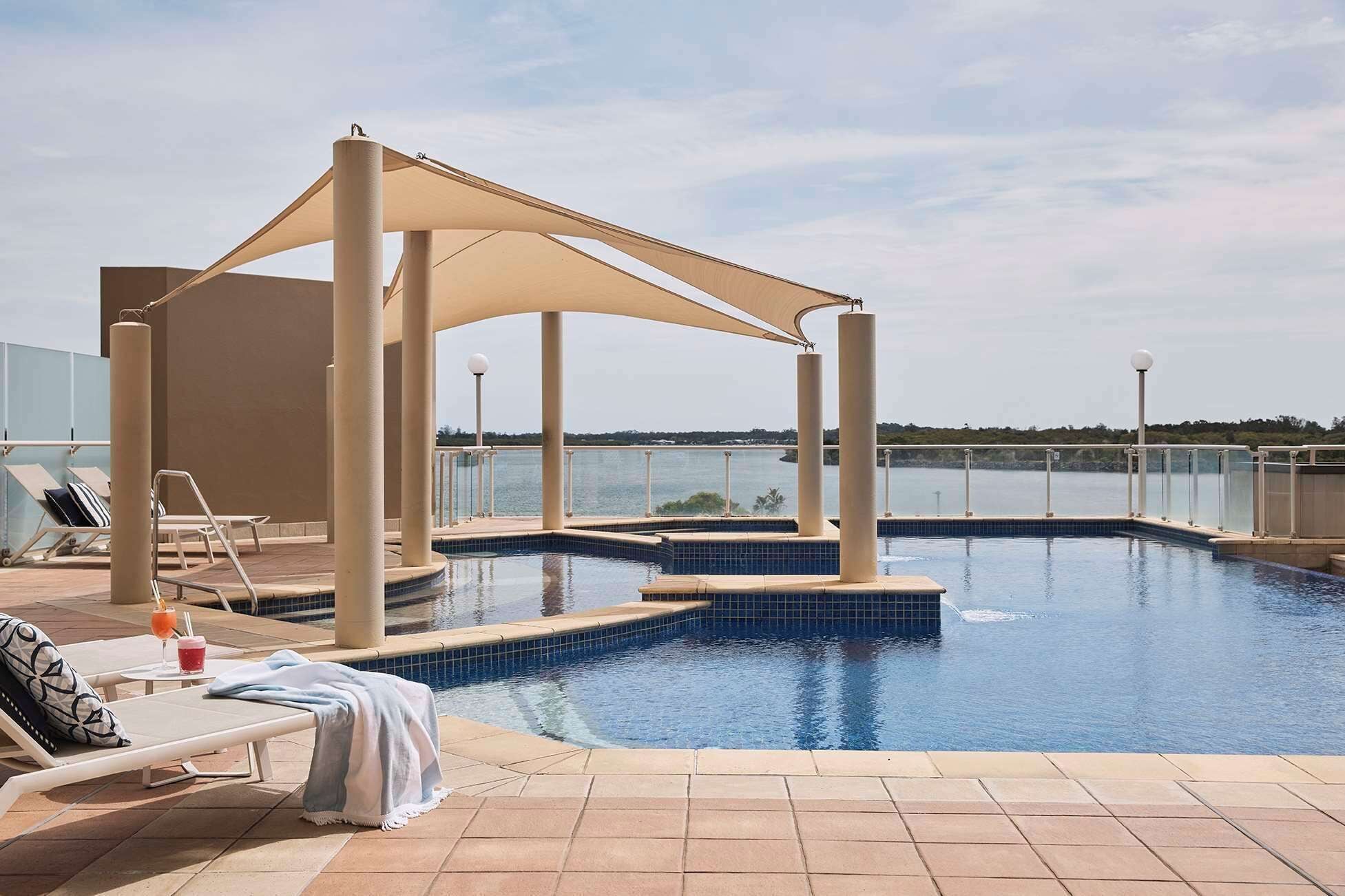 Un área de piscina con sillones de descanso y una pérgola.