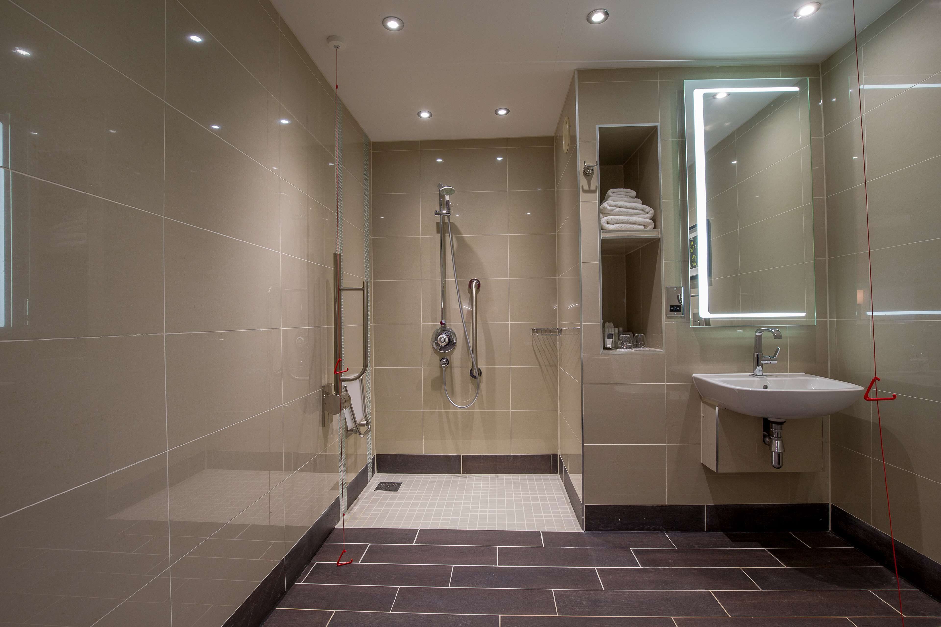 A modern bathroom with a walk-in shower, a sink, and a mirror.