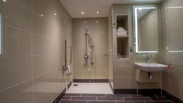A modern bathroom with a walk-in shower, a sink, and a mirror.