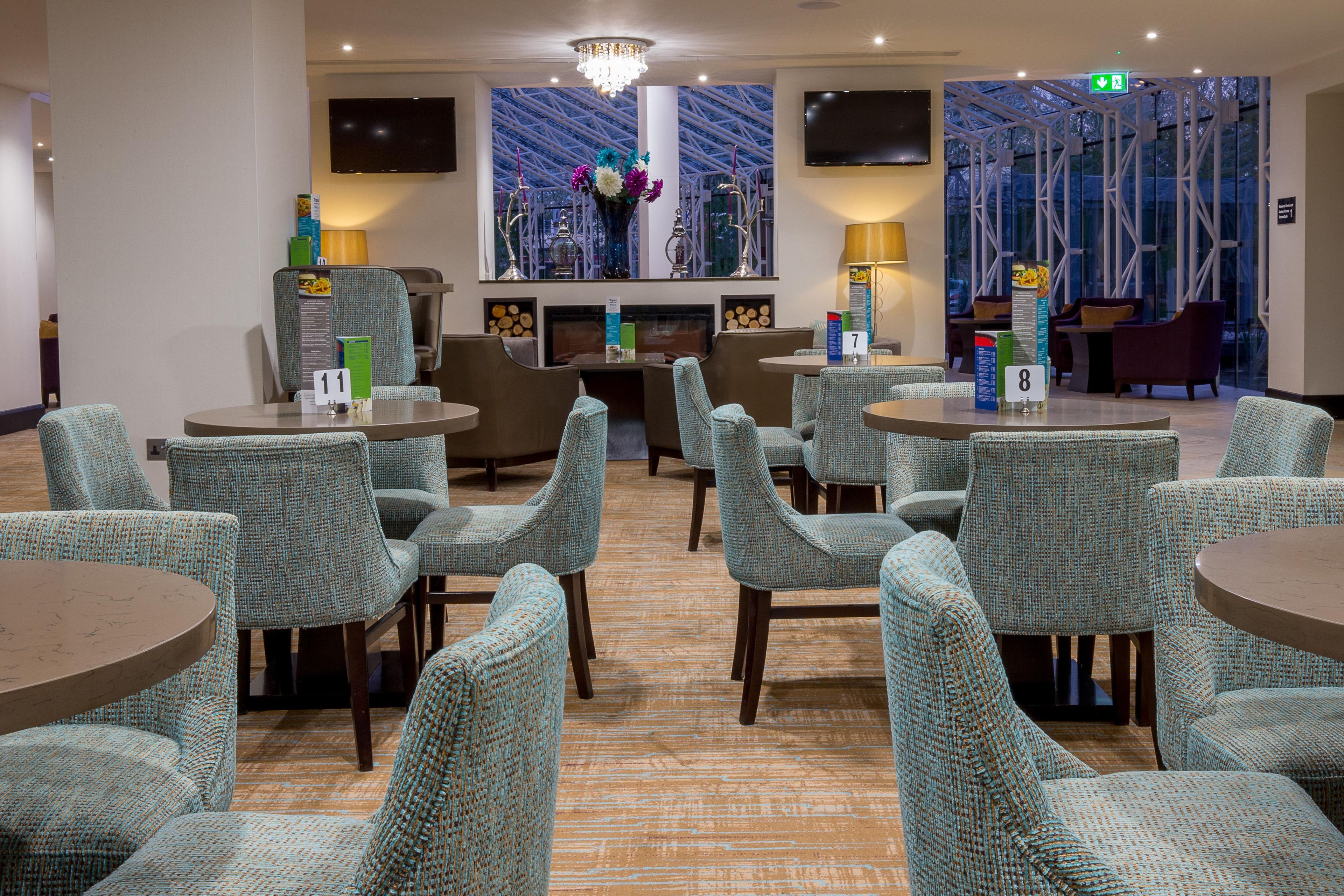 A hotel lobby with seating areas, a fireplace, and a large window with a view.