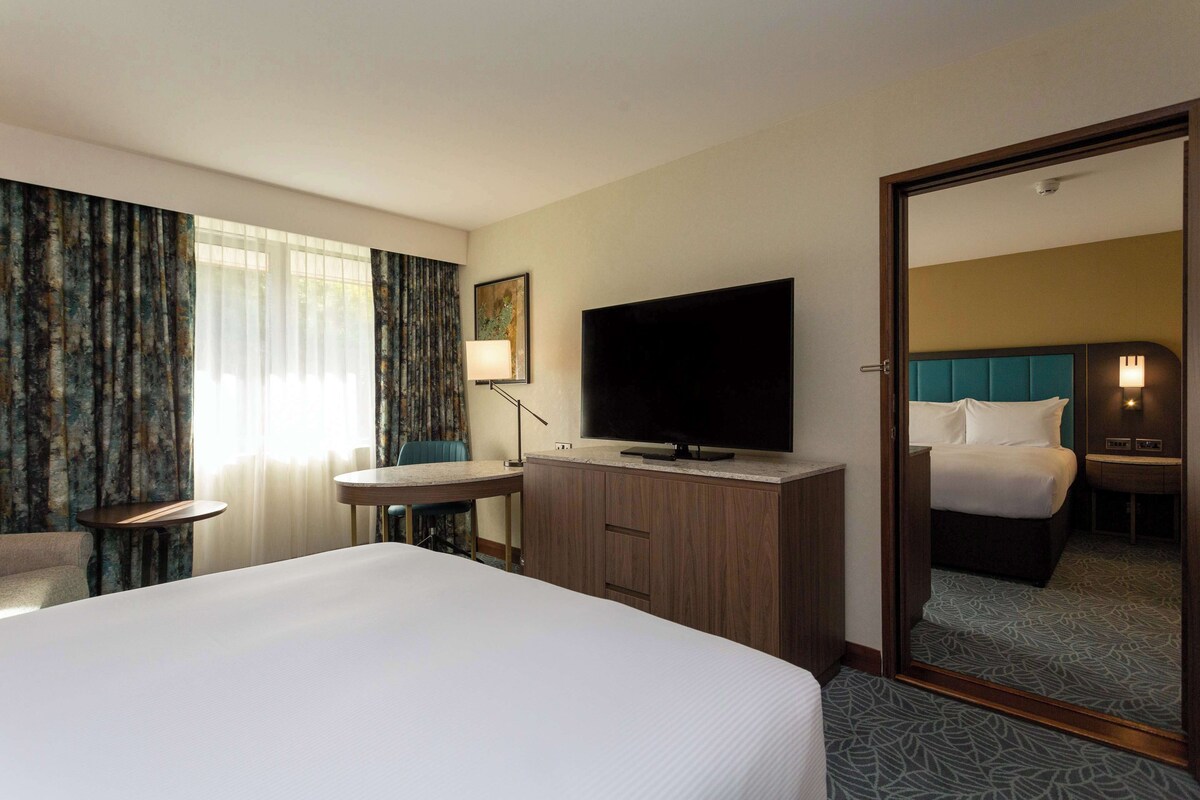 Een hotelkamer met een groot bed, een bureau, een televisie en een spiegel.