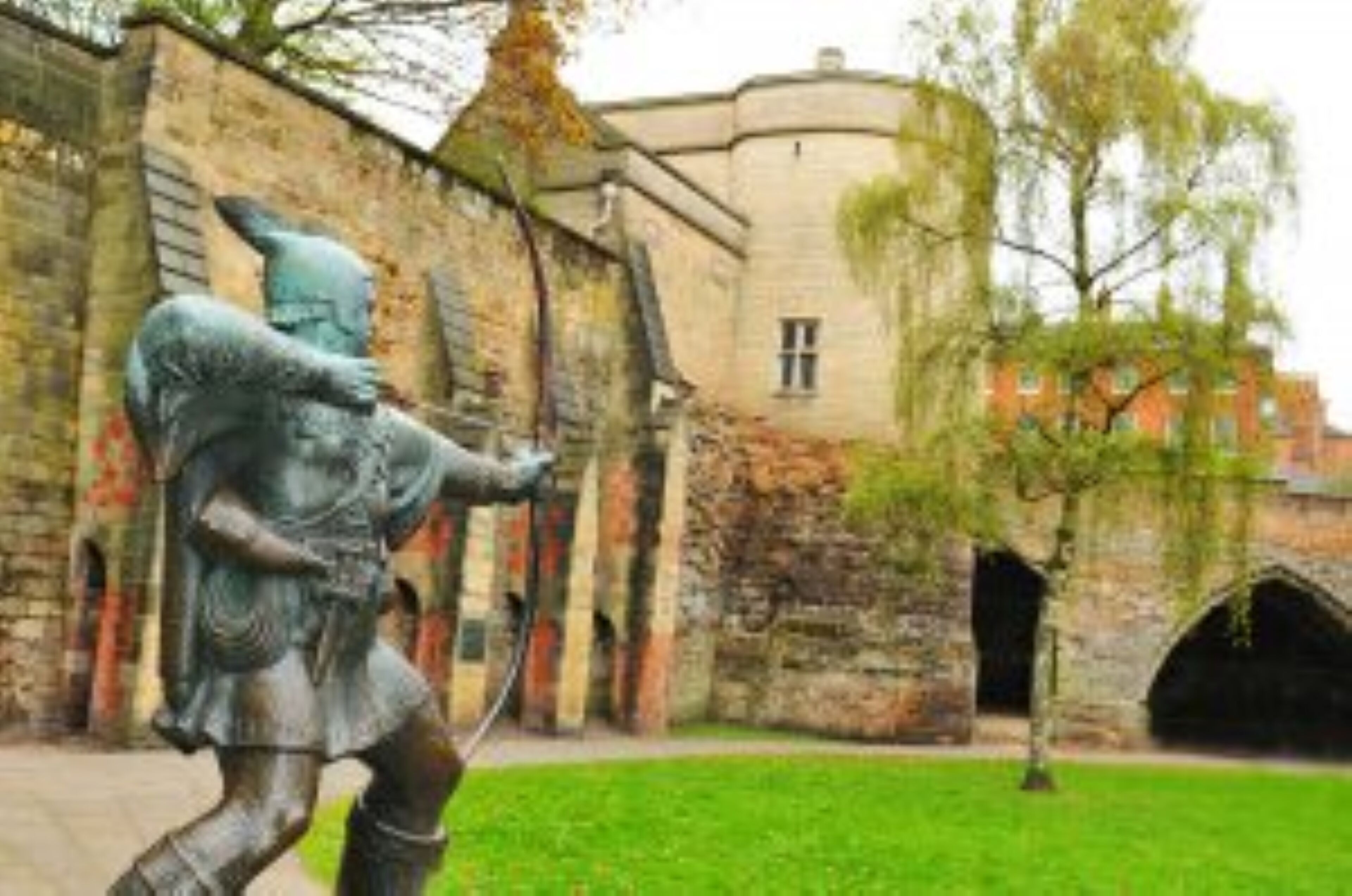 A statue of a knight in armor, a stone building with arched windows, and a grassy courtyard.