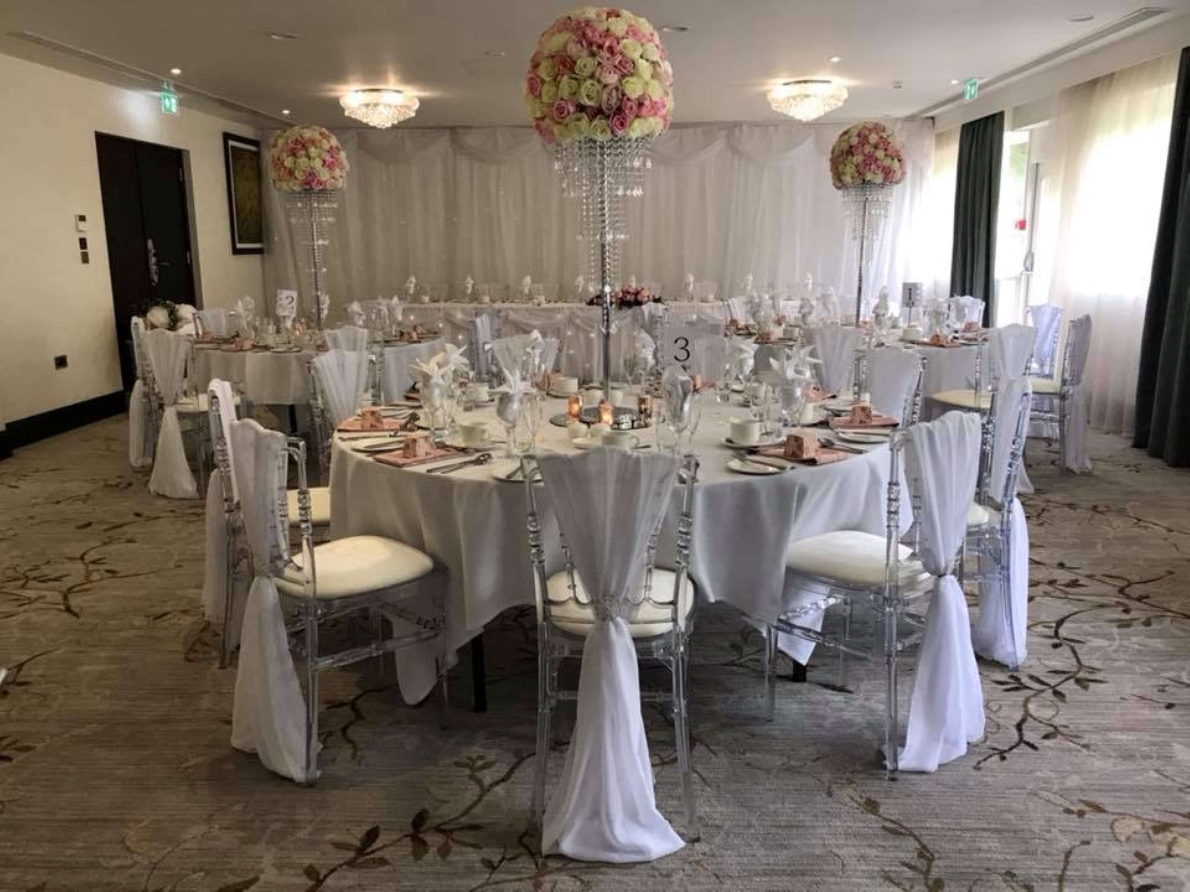 A banquet hall with round tables, white tablecloths, and chairs with white sashes.