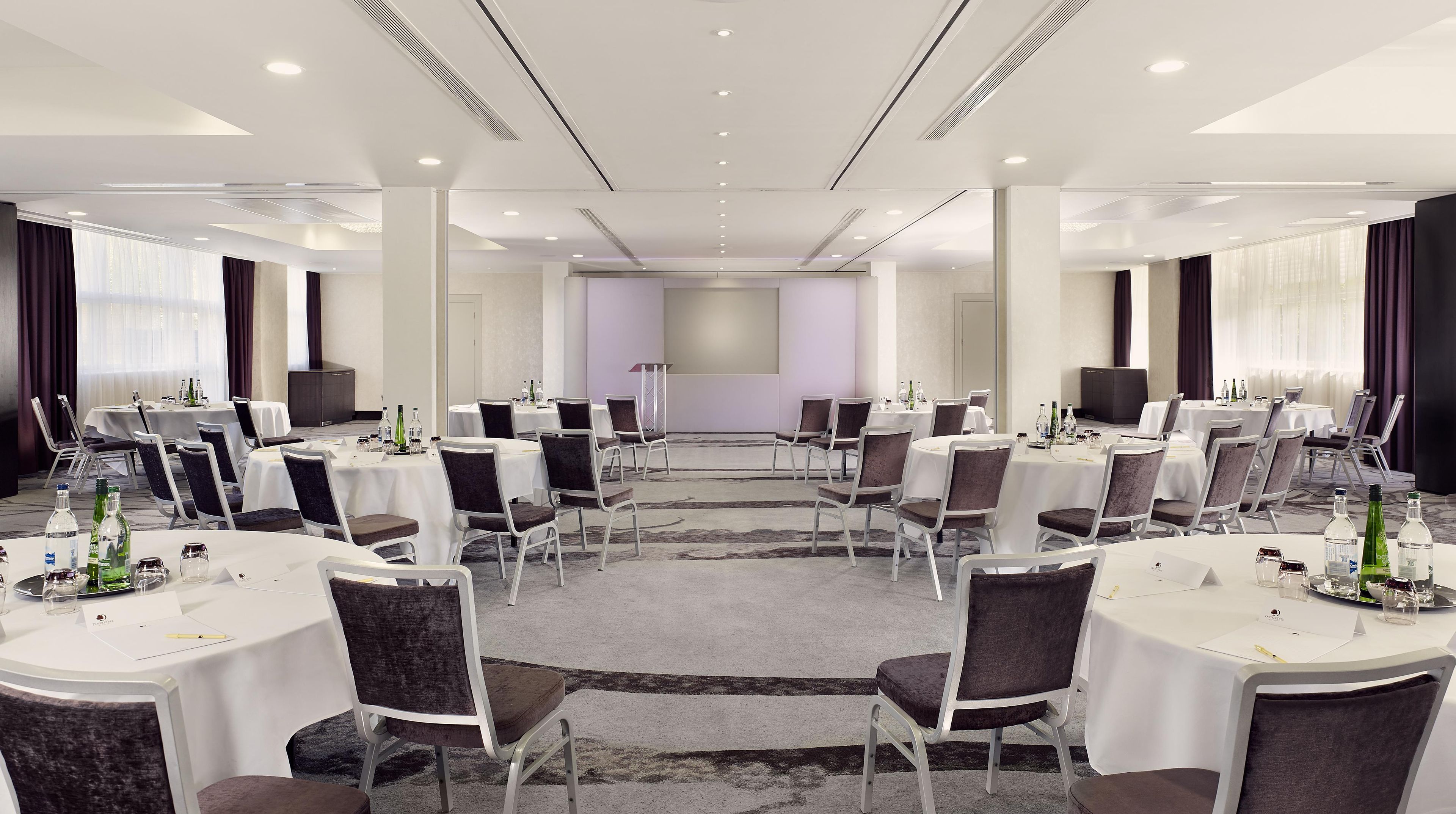 A conference room with round tables, chairs, and a podium.