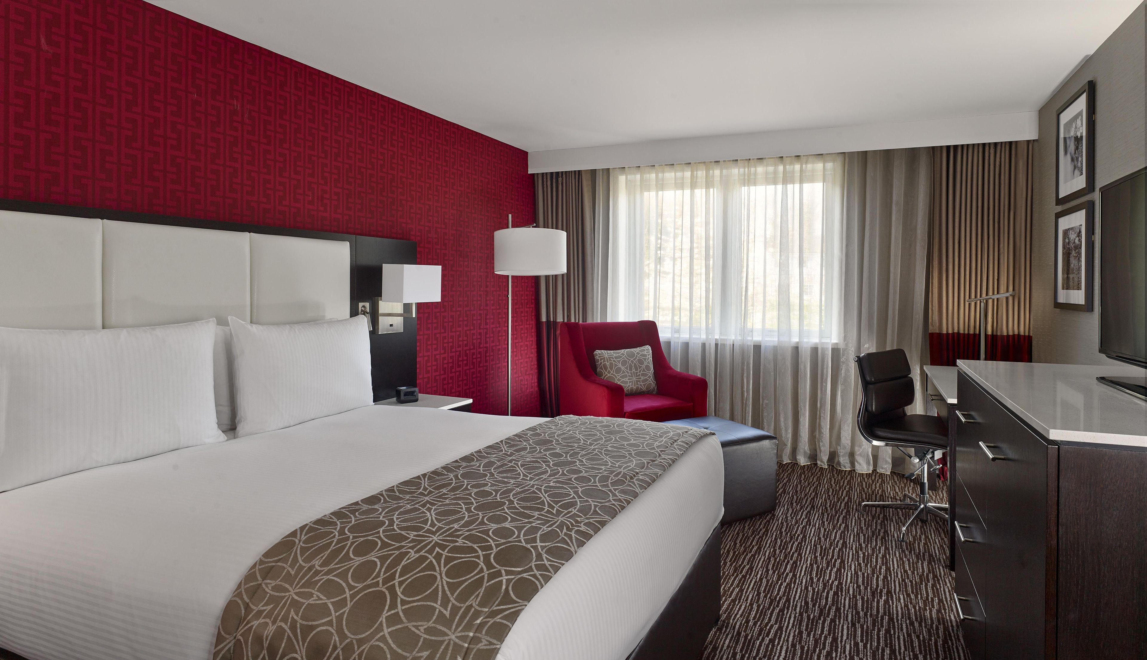 Une chambre d’hôtel avec un grand lit, un bureau, une chaise et un téléviseur.