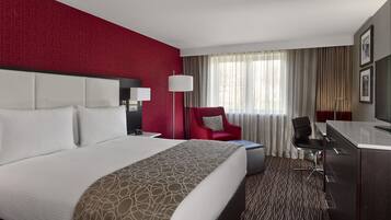 Une chambre d’hôtel avec un grand lit, un bureau, une chaise et un téléviseur.