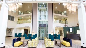 Spaziosa hall con diverse zone salotto, un ascensore centrale e una reception.