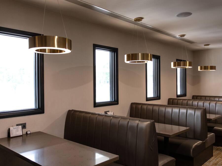 A restaurant interior with booth seating, pendant lighting, and large windows.