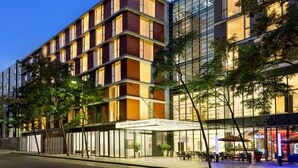 Un hotel moderno con varios pisos, ventanas amplias y zonas de estar al aire libre.