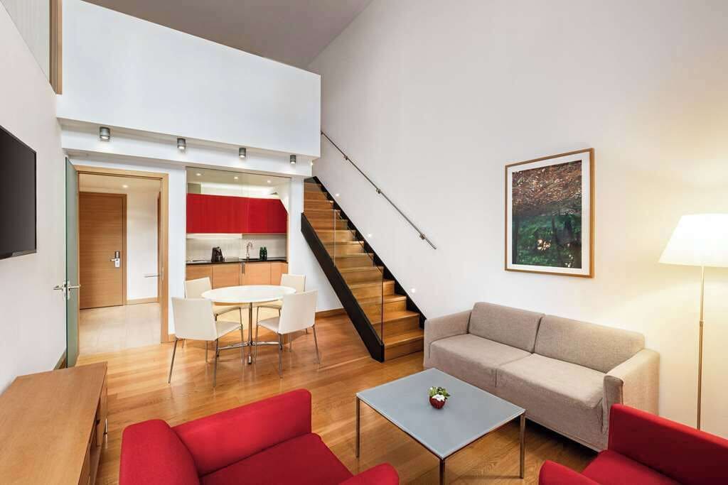 Una sala moderna con un sofá, una mesa de centro y una zona de comedor con sillas.