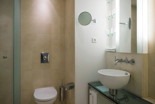 Un baño moderno con inodoro, lavamanos, espejo y cabina de ducha de vidrio.