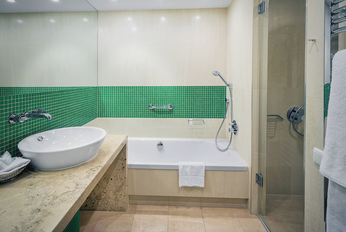 Une salle de bain moderne dotée d’une grande baignoire, d’un lavabo séparé et d’un espace douche.