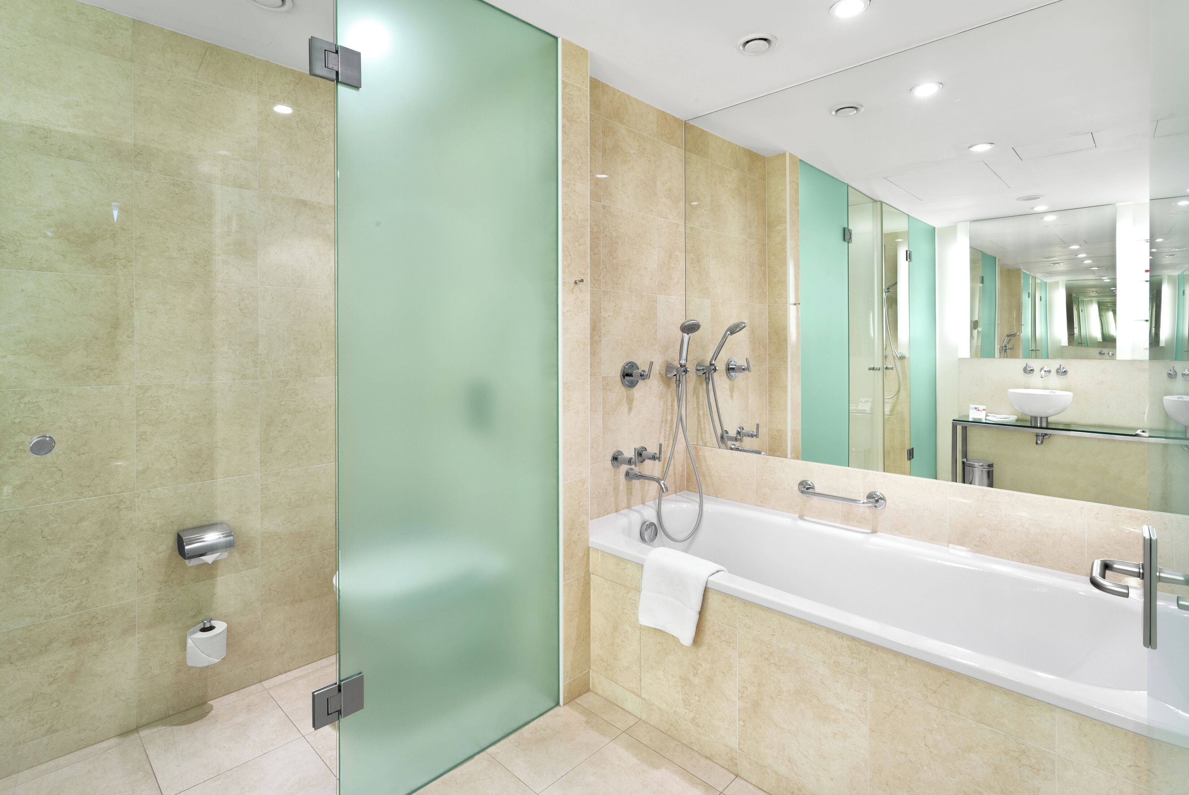 Un baño moderno con cabina de ducha de vidrio, una bañera independiente y un espejo grande sobre el lavabo.